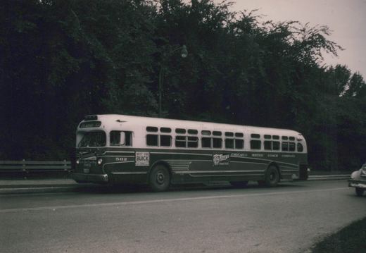 A vintage motor bus with number 582 and Chicago Motor Coach Company lettering is driving down a tree-lined street.