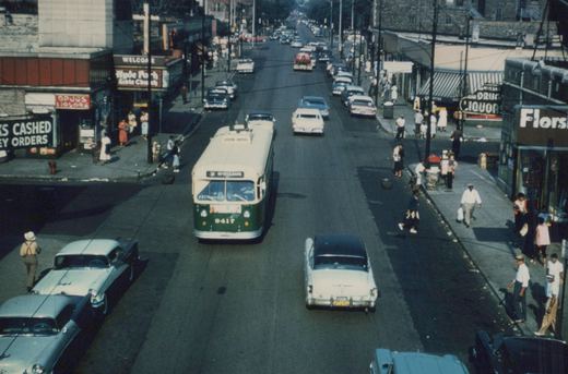 A green and cream trolleybus with the number 9417 and destination sign reading '51 ST-LOUIS' travels down a city street lined with 1950s cars and pedestrians, with storefronts including 'Hyde Park Bible Church' and 'Florsheim' visible.
