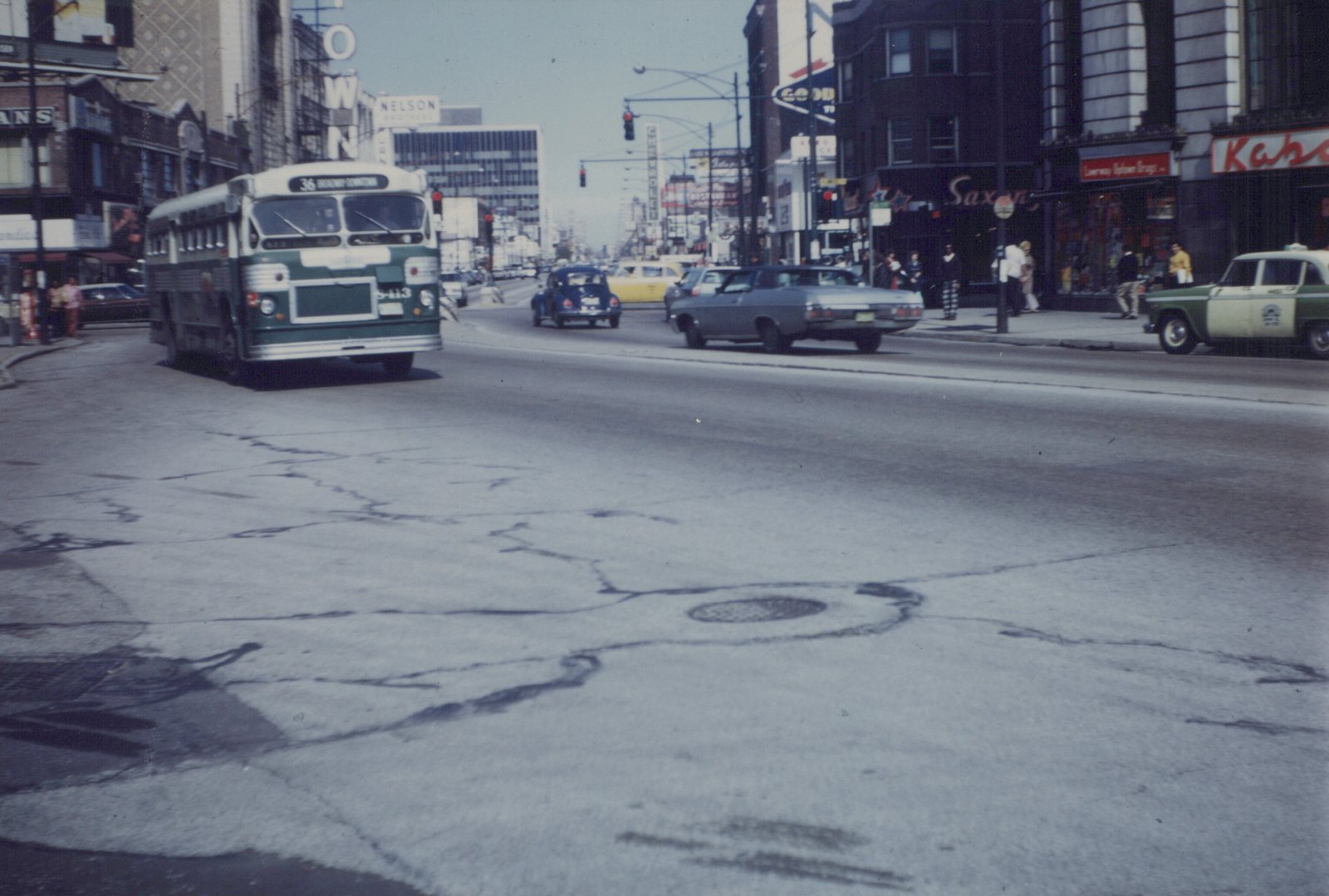 A vintage Chicago Transit Authority bus, number 8413, is driving down a busy city street lined with storefronts and cars from the 1960s or 1970s.