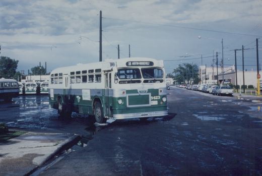 A green and white Chicago Transit Authority bus, number 3423, on route 91 to Austin-Roosevelt, is parked on a wet street with other buses and cars in the background under an overcast sky.