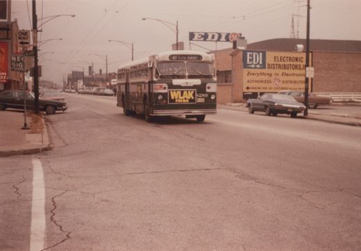 A green and white bus with the number 8289 and route 41 Elston-Milwaukee displayed on its front is driving down a cracked city street, with a sign for EDI Electronic Distributors visible in the background.