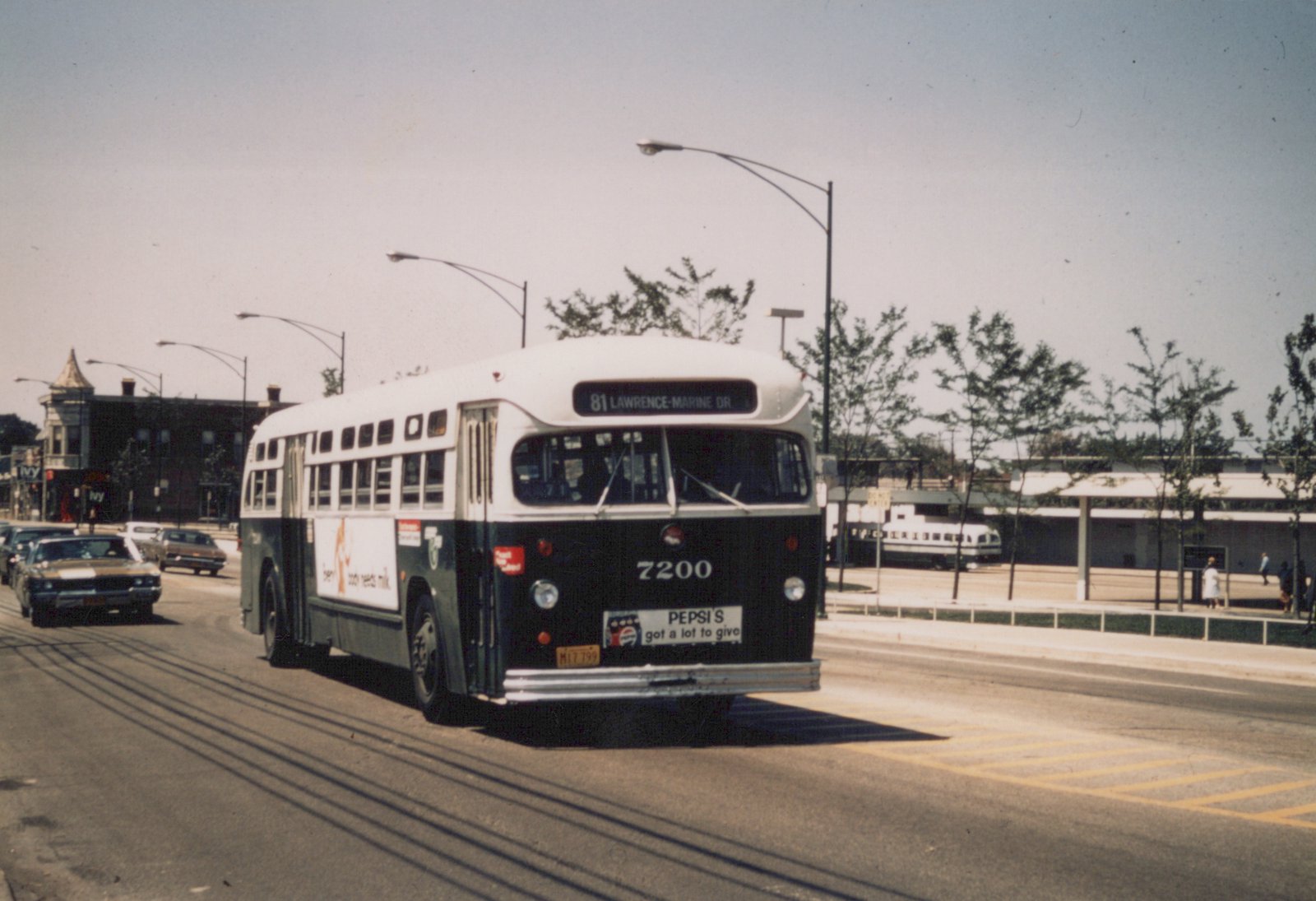 A white and green Chicago Transit Authority motor bus, number 7200, is shown driving on a city street with 1970s cars and buildings in the background.