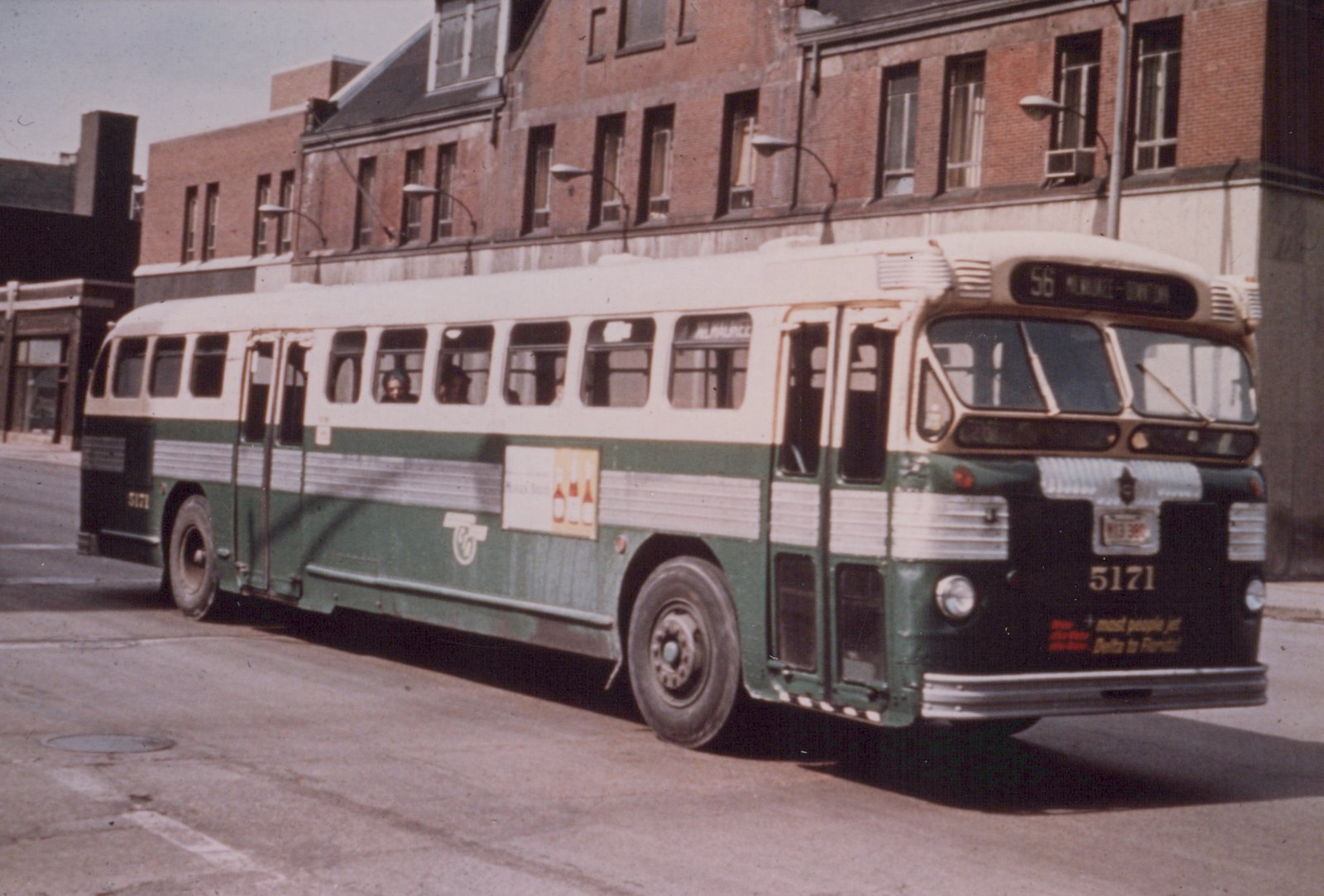 A green and white Milwaukee Road bus, number 5171, is parked on a city street with its destination sign reading '56 MILWAUKEE - DOWNTOWN' and passengers visible inside.