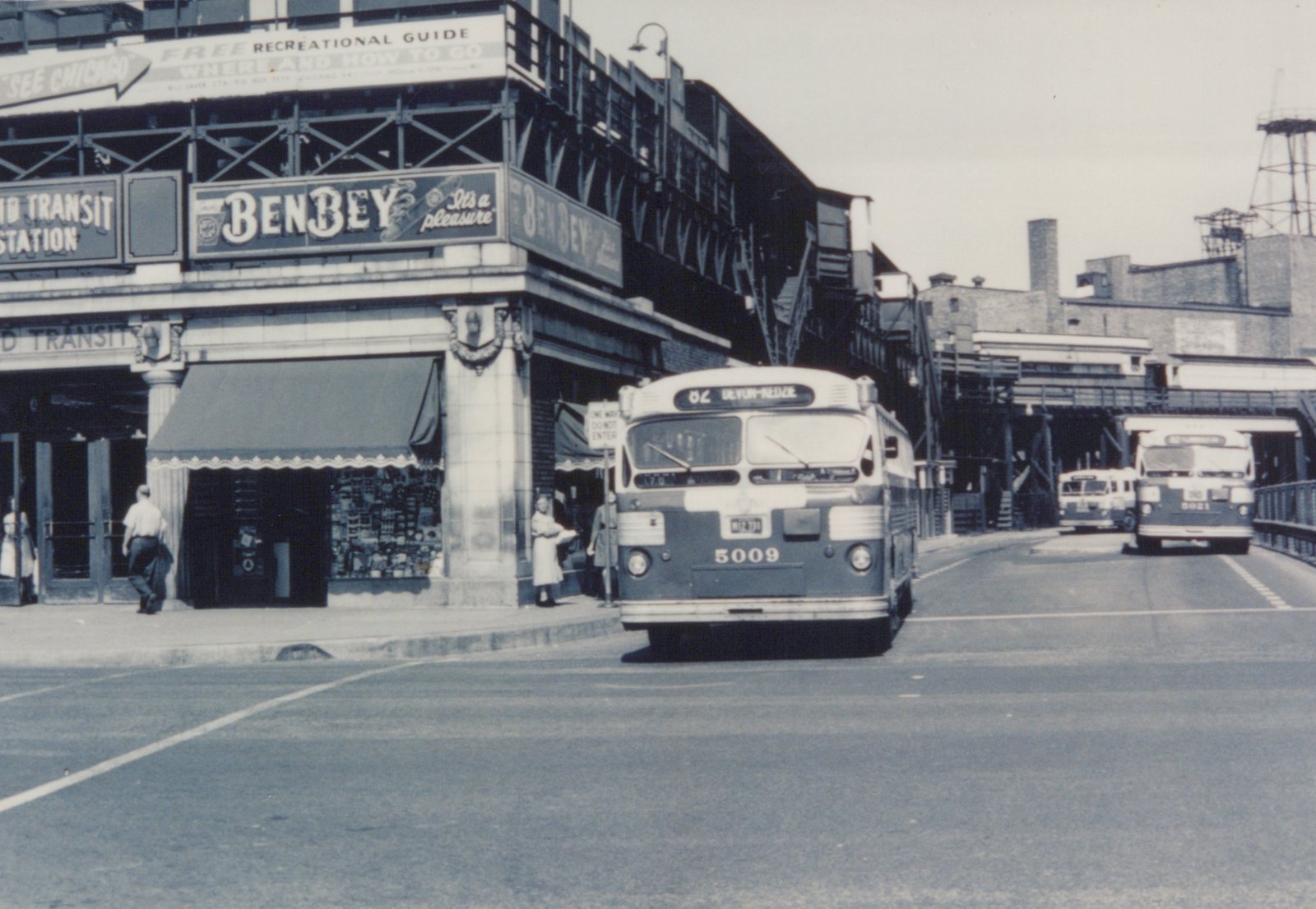 A vintage black and white photo of a Chicago Transit Authority bus on a city street, with a Ben-Bey sign on a building and other buses in the background.