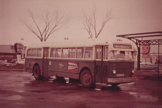A vintage CTA bus with the number 3662 on its front, parked on a street with wet pavement in winter, with a car wash and bare trees visible in the background.