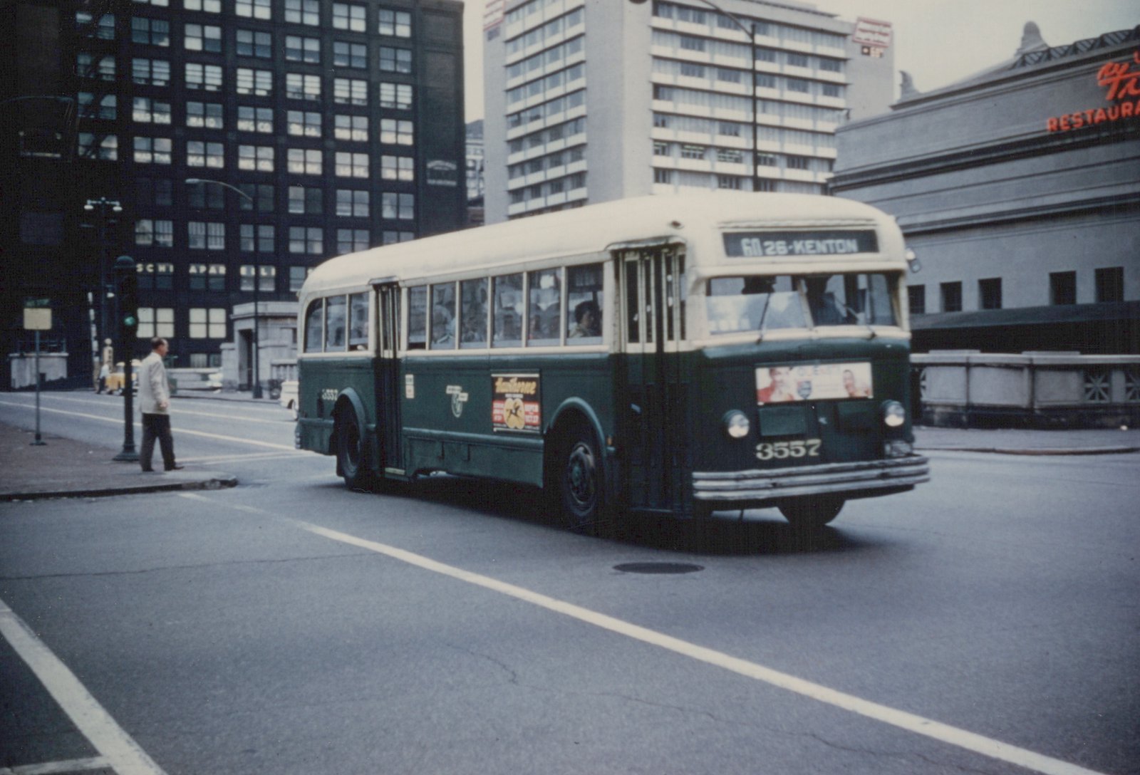 A green and cream Chicago Transit Authority bus, number 3557, on a city street with tall buildings in the background.