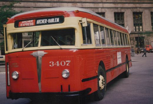 A red and cream CTA bus, number 3407, is parked on a city street with a destination sign reading 'ARCHER EXPRESS ARCHER-HARLEM' and pedestrians nearby.