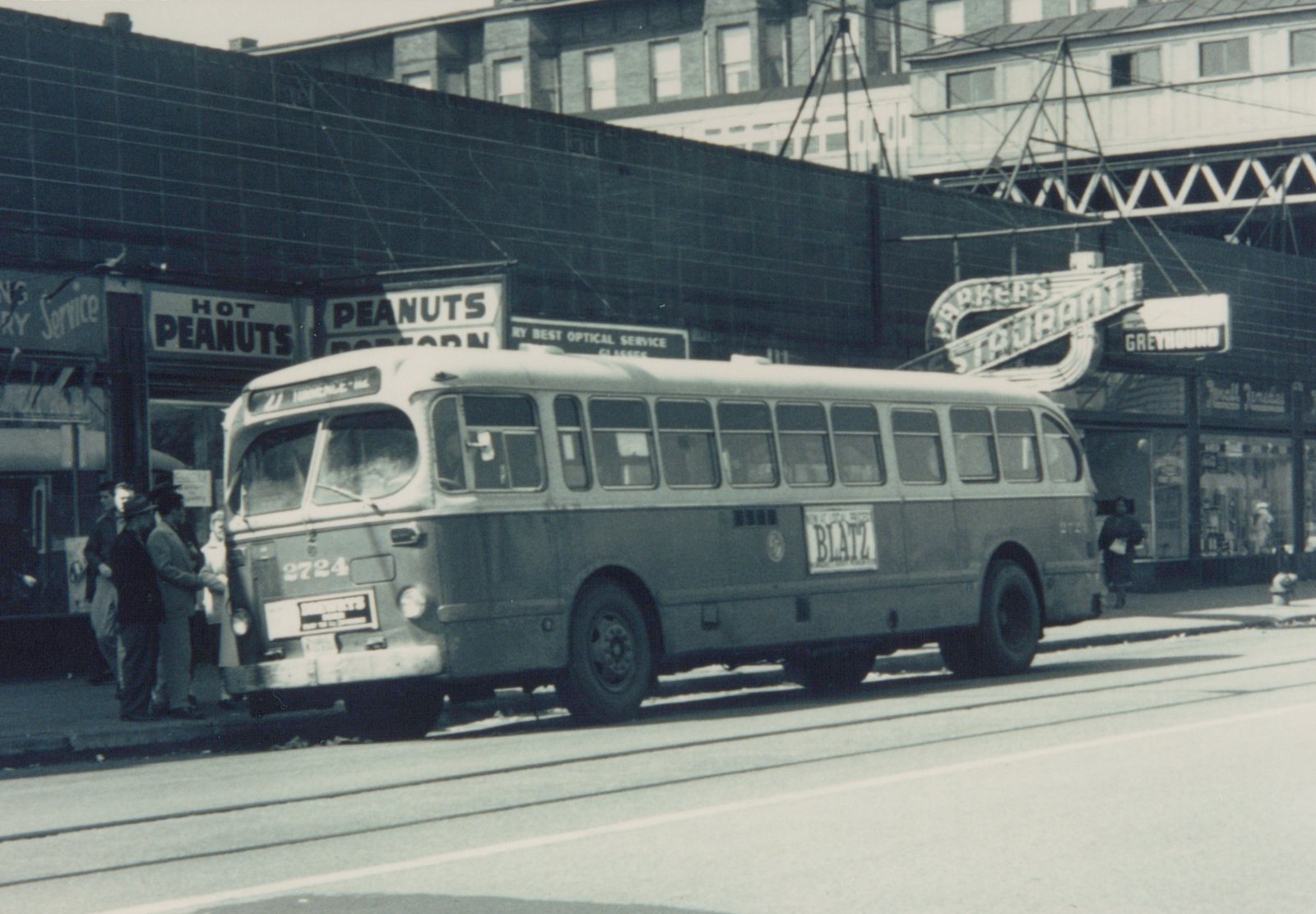 A vintage photo show a CTA bus on a city street with people boarding and various store signs including 'HOT PEANUTS' and 'GREYHOUND' in the background.