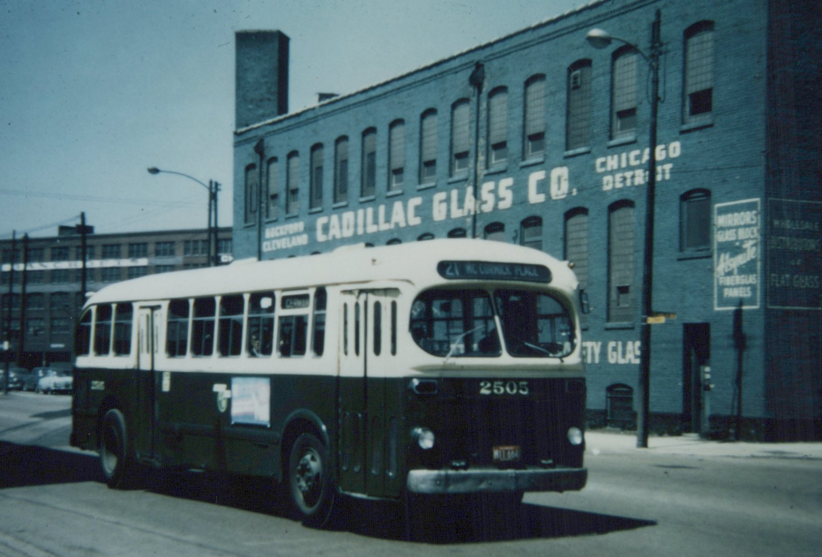 A vintage green and cream CTA bus, number 2505, is shown from a front three-quarter view on a city street, with a large brick building labeled 'Cadillac Glass Co.' in the background.
