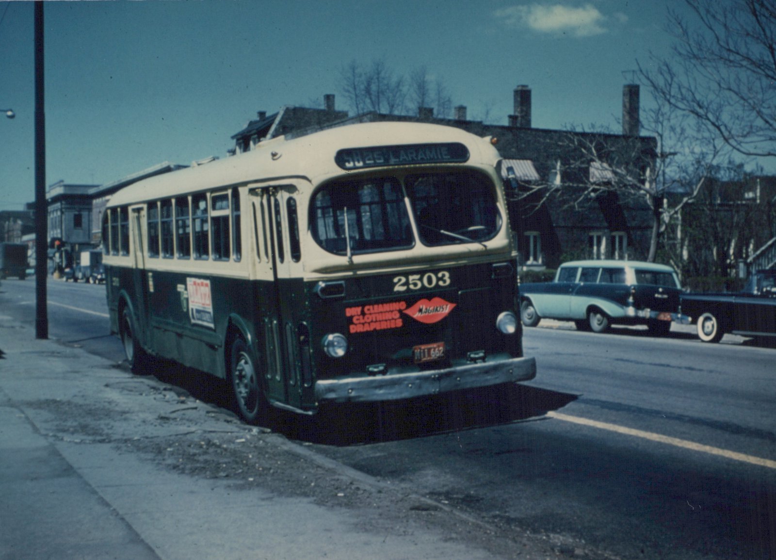 A vintage CTA bus numbered 2503 is parked on a city street, displaying a route sign for '58 25 LARAMIE' and an ad for 'Magikist' dry cleaners, with 1950s cars in the background.