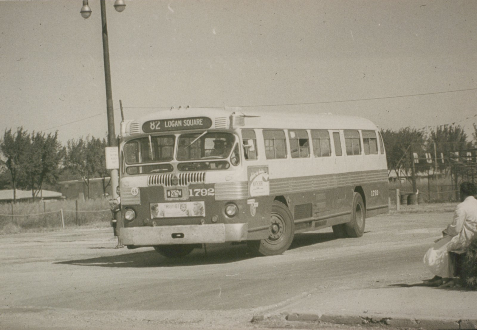 A vintage black-and-white photo shows a CTA motor bus, number 1792, on route 82 to Logan Square, parked on a street with a person waiting nearby.