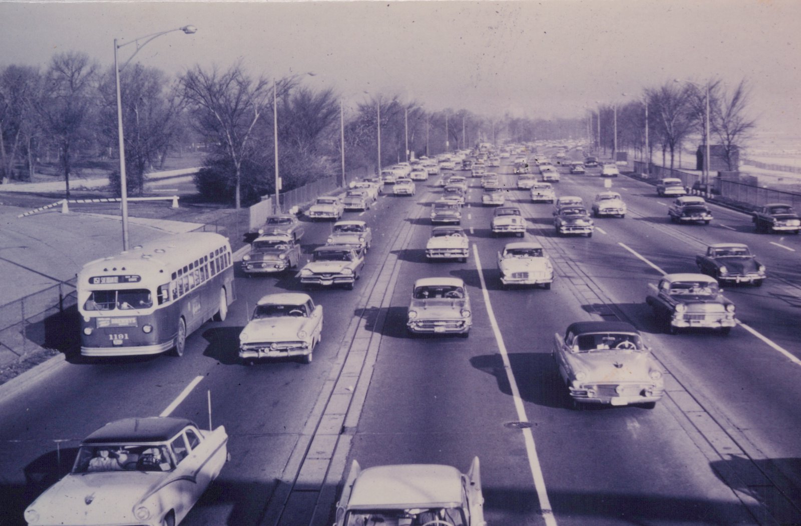A black and white photo of a Chicago Transit Authority bus with the number 1181 and destination '63 STONEY ISLAND' driving on a multi-lane expressway filled with 1950s cars and surrounded by bare trees.