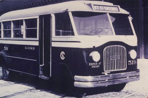 Black-and-white photo of a vintage Superior motor bus, number 519, with 'ILL. C.C. No. 19' on its side, parked on a city street with snow on the ground.
