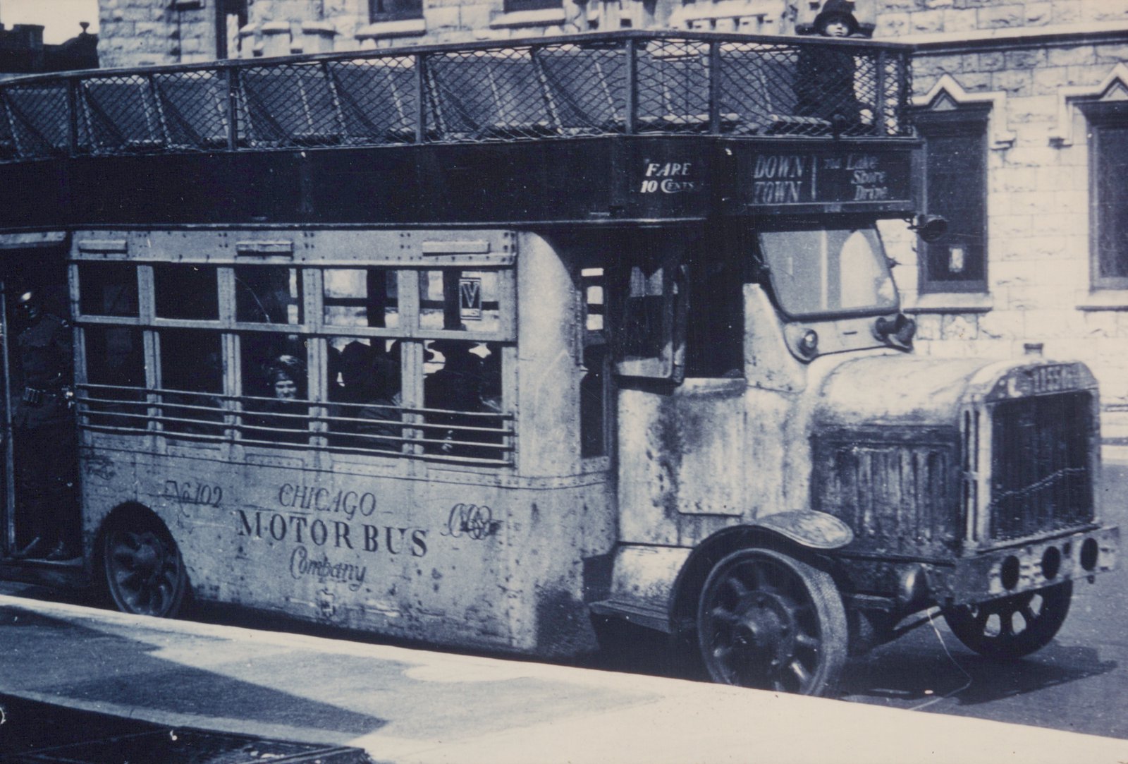 A vintage black-and-white photo of a double-decker bus with 'Chicago Motor Bus Company' lettering on its side and number 1155 on its front, showing passengers on the upper deck and a clear destination sign.