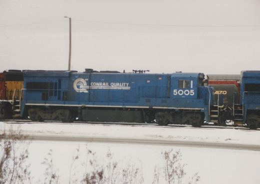 Side view of a blue Conrail diesel locomotive number 5005 in a snowy yard, with 'CONRAIL QUALITY' lettering on its side.