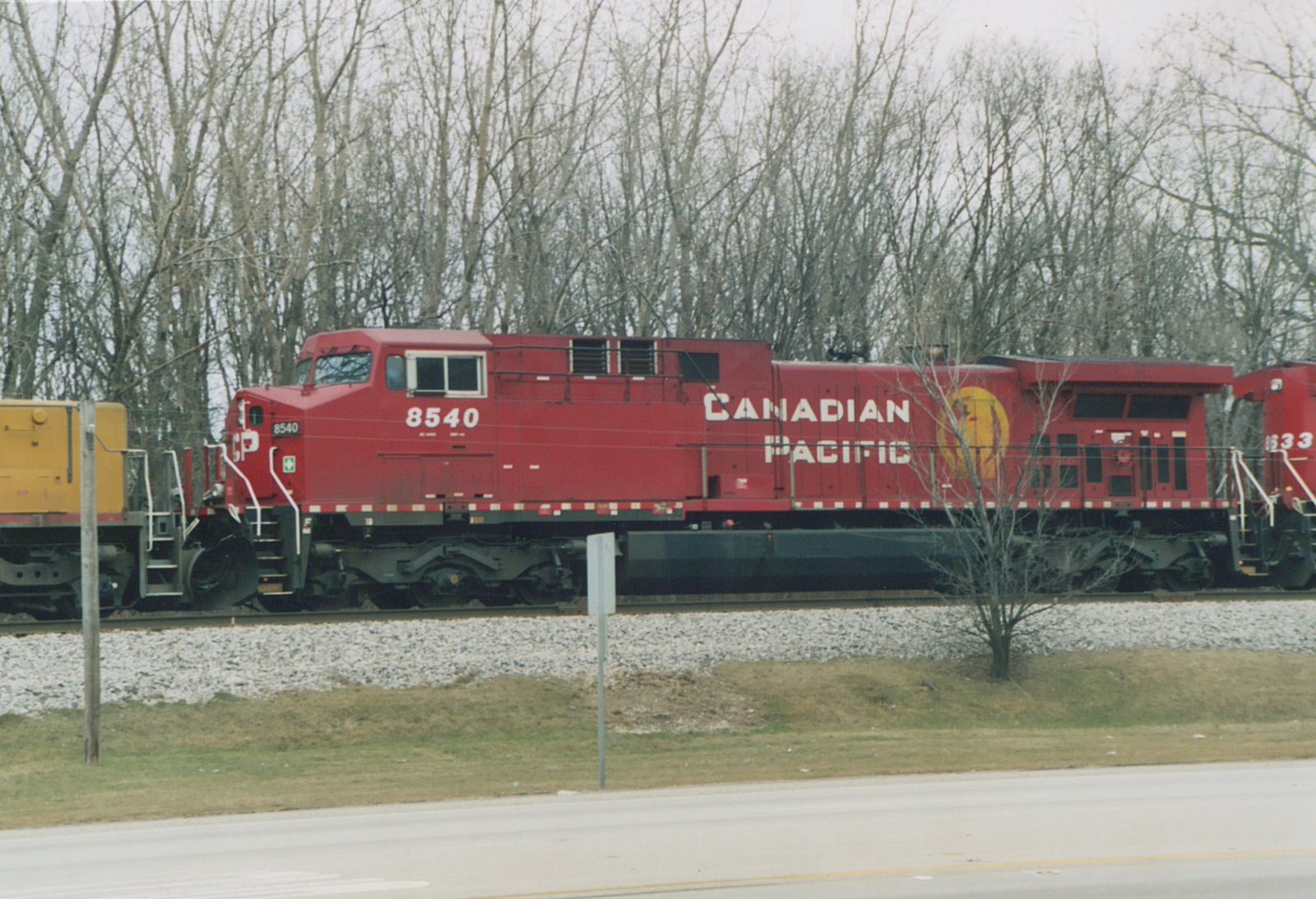 A red Canadian Pacific diesel locomotive numbered 8540 is shown on a railroad track with bare trees in the background.
