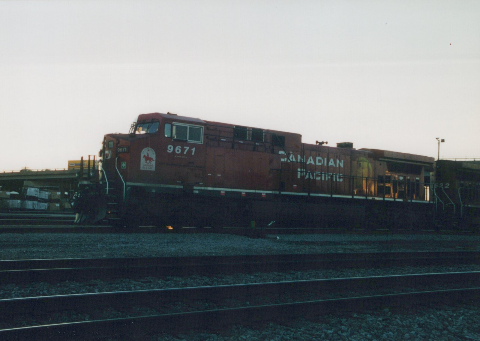 Side view of a red Canadian Pacific diesel locomotive numbered 9671 in a rail yard at dusk, with a second locomotive numbered 8522 behind it.