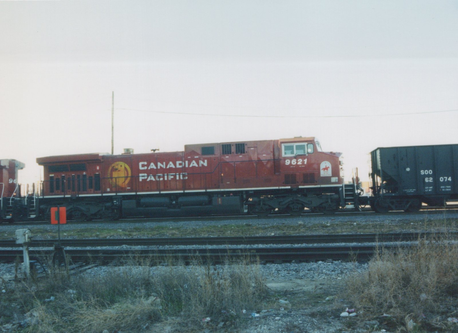 Side view of a red Canadian Pacific diesel locomotive, number 9621, standing on tracks in a yard with a black freight car nearby.