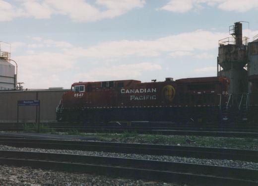 A red Canadian Pacific diesel locomotive numbered 8547 is parked on the tracks at Mannheim station platform under a cloudy sky.