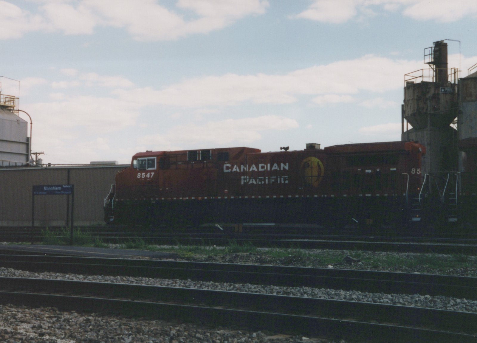 A red Canadian Pacific diesel locomotive numbered 8547 is parked on the tracks at Mannheim station platform under a cloudy sky.