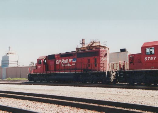 Two red CP Rail System SD40 diesel locomotives, numbered 5641 and 5757, are coupled together on a set of parallel tracks in a rail yard on a sunny day.