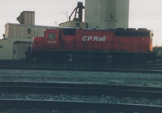 A red CP Rail diesel locomotive, number 4617, sits on tracks in a yard with industrial buildings in the background.