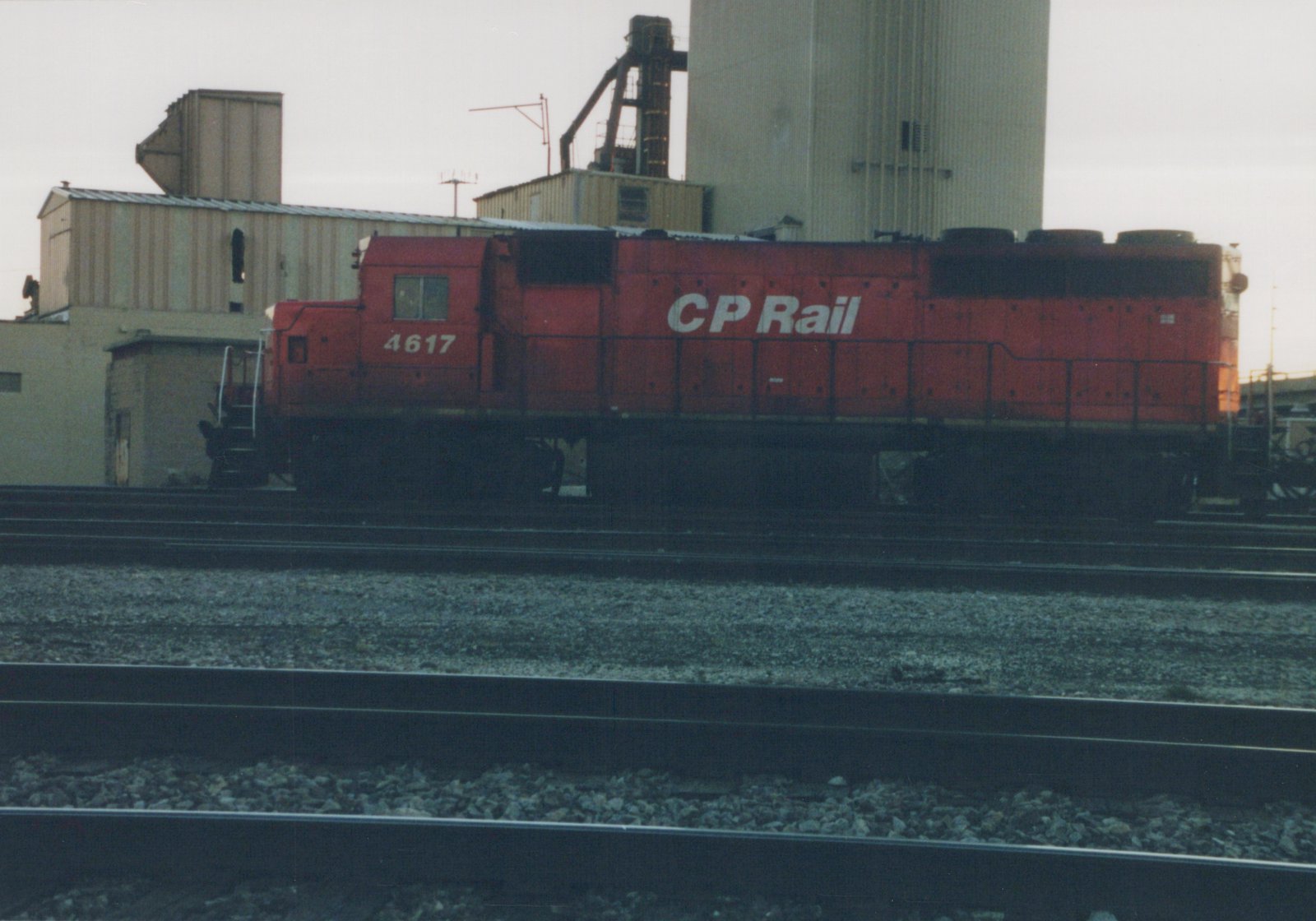 A red CP Rail diesel locomotive, number 4617, sits on tracks in a yard with industrial buildings in the background.