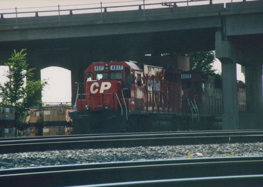 A red Canadian Pacific locomotive with the number 4617 is seen under a concrete overpass, with another locomotive, number 4620, following behind.