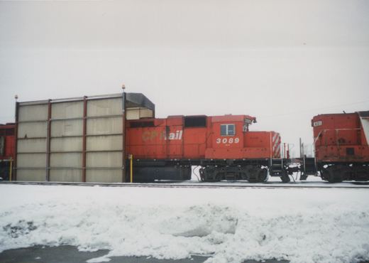 Two Canadian Pacific diesel locomotives, numbers 3089 and 401, are parked side by side on a snow-covered rail yard under an overcast sky.