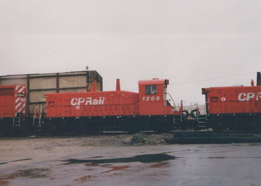 A side view of two red and black CP Rail locomotives, numbered 1206 and 50, parked in an industrial rail yard under an overcast sky.