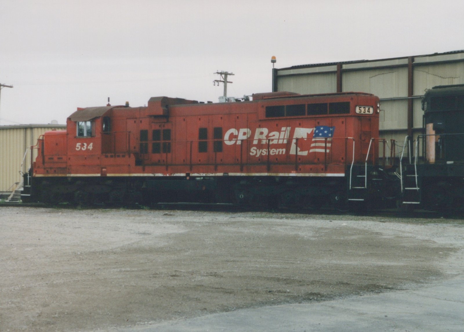 A red CP Rail System diesel locomotive, number 534, is parked in a yard on an overcast day.