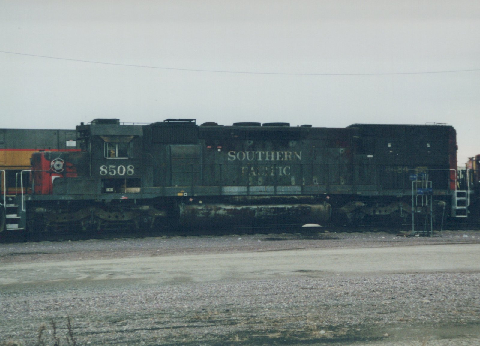 A side view of a Southern Pacific diesel locomotive, number 8508, painted black and standing in a gravel rail yard on a cloudy day.