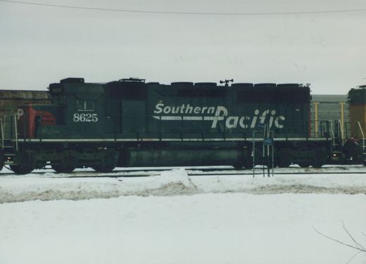 A side view of a black Southern Pacific diesel locomotive with white lettering and the number 8625, standing on tracks in a snowy yard.