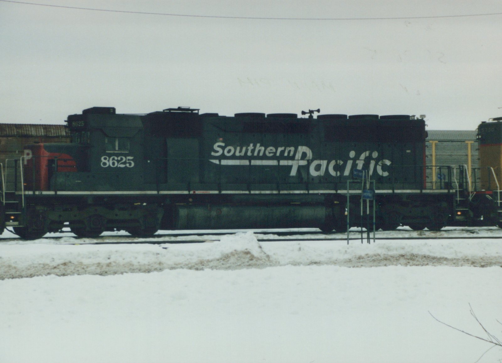 A side view of a black Southern Pacific diesel locomotive with white lettering and the number 8625, standing on tracks in a snowy yard.