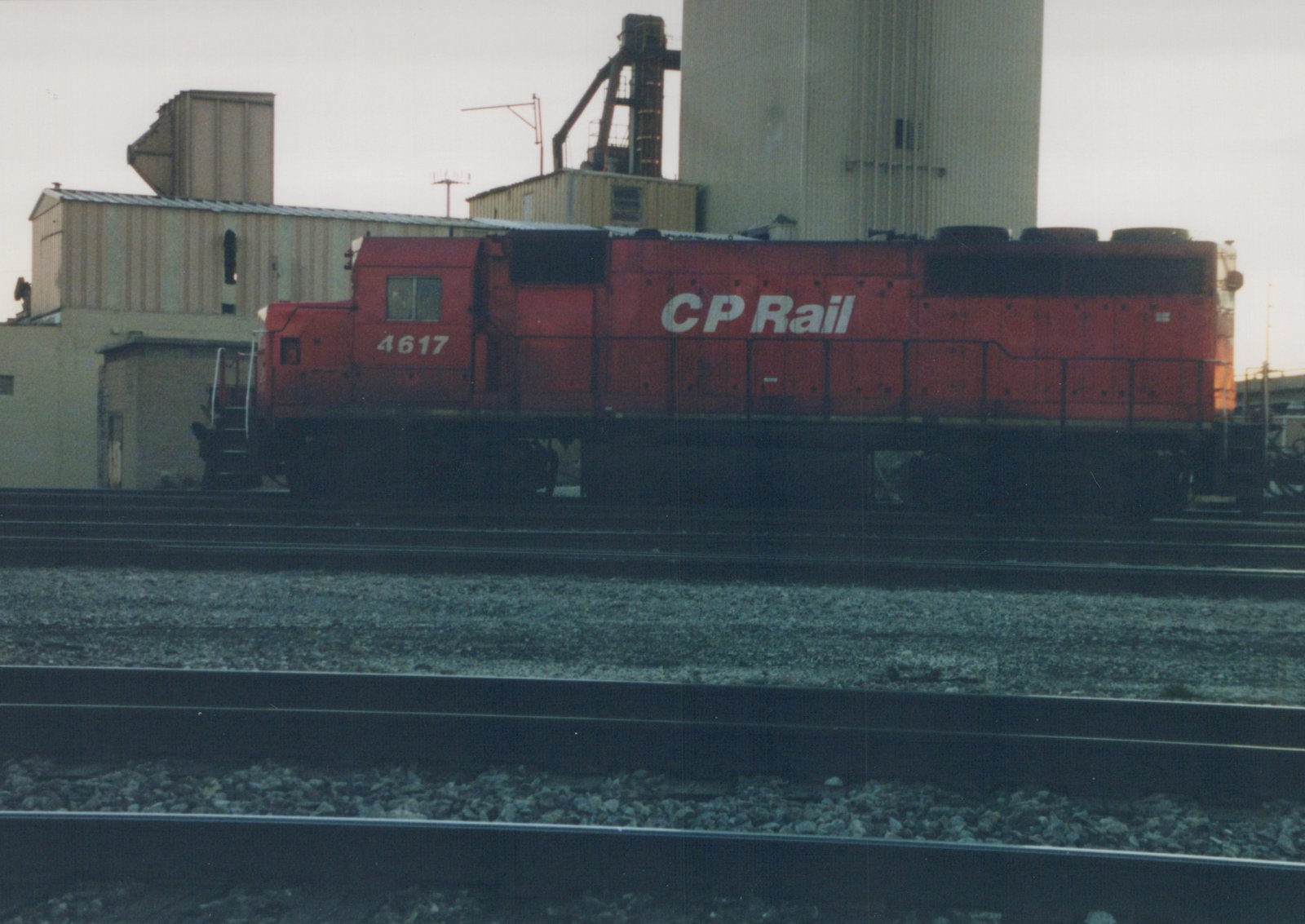 A red Canadian Pacific diesel locomotive, number 4617, stands on multiple tracks in an industrial yard under an overcast sky.