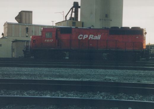 A red Canadian Pacific diesel locomotive, number 4617, stands on multiple tracks in an industrial yard under an overcast sky.