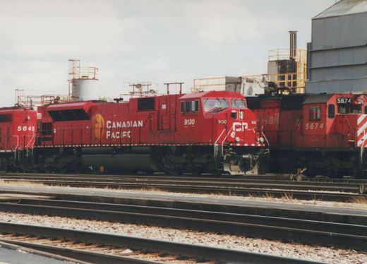 Three red Canadian Pacific SD40-2 diesel locomotives numbered 9130, 5645, and 5674 are parked side-by-side on multiple tracks in a rail yard under a cloudy sky.