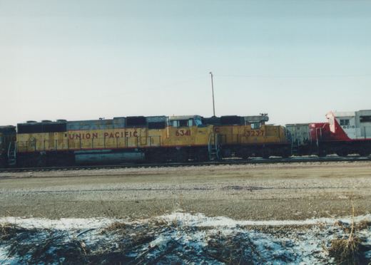 Two yellow Union Pacific diesel locomotives, numbered 6341 and 3237, sit side by side on railroad tracks in a yard with patches of snow on the ground.