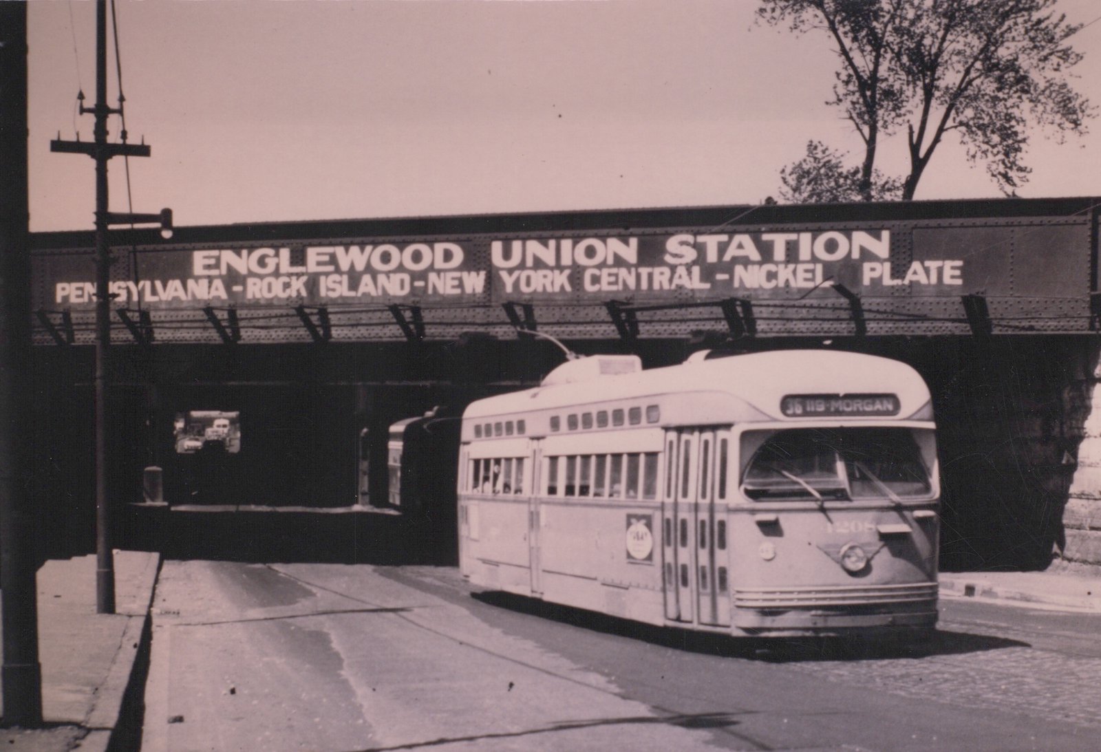 A black and white photograph of a classic PCC streetcar in Chicago, numbered 1208 and heading for Morgan Street, passing under a large bridge sign for Englewood Union Station.