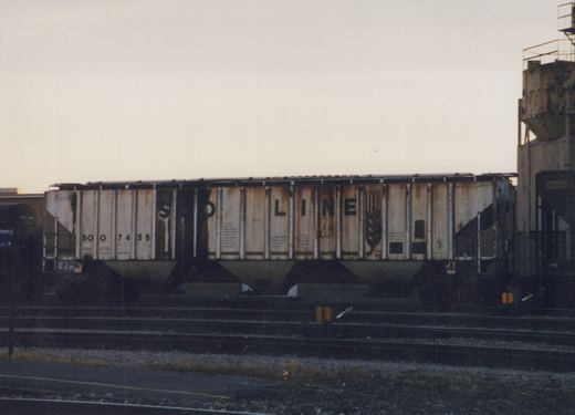 A side view of a Soo Line freight car, number 7455, parked on tracks in a rail yard during dusk.