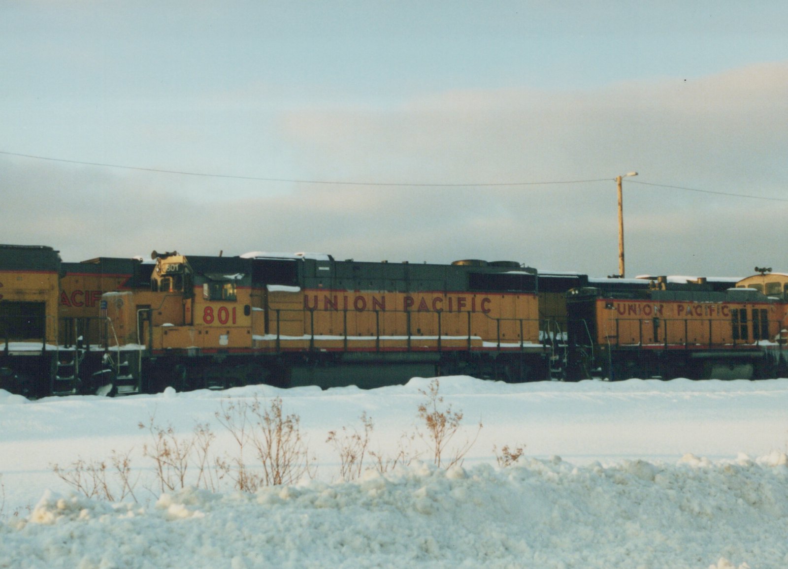 A side view of two Union Pacific diesel locomotives, number 801 visible on the front, parked in a snow-covered yard under an overcast sky.