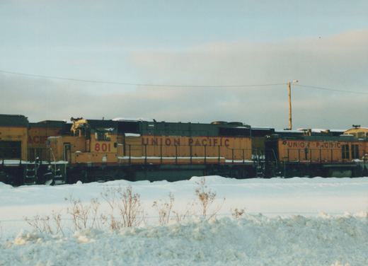 A side view of two Union Pacific diesel locomotives, number 801 visible on the front, parked in a snow-covered yard under an overcast sky.