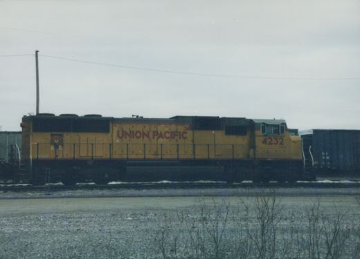 A side view of a yellow and green Union Pacific diesel locomotive, number 4232, parked in a snowy yard.