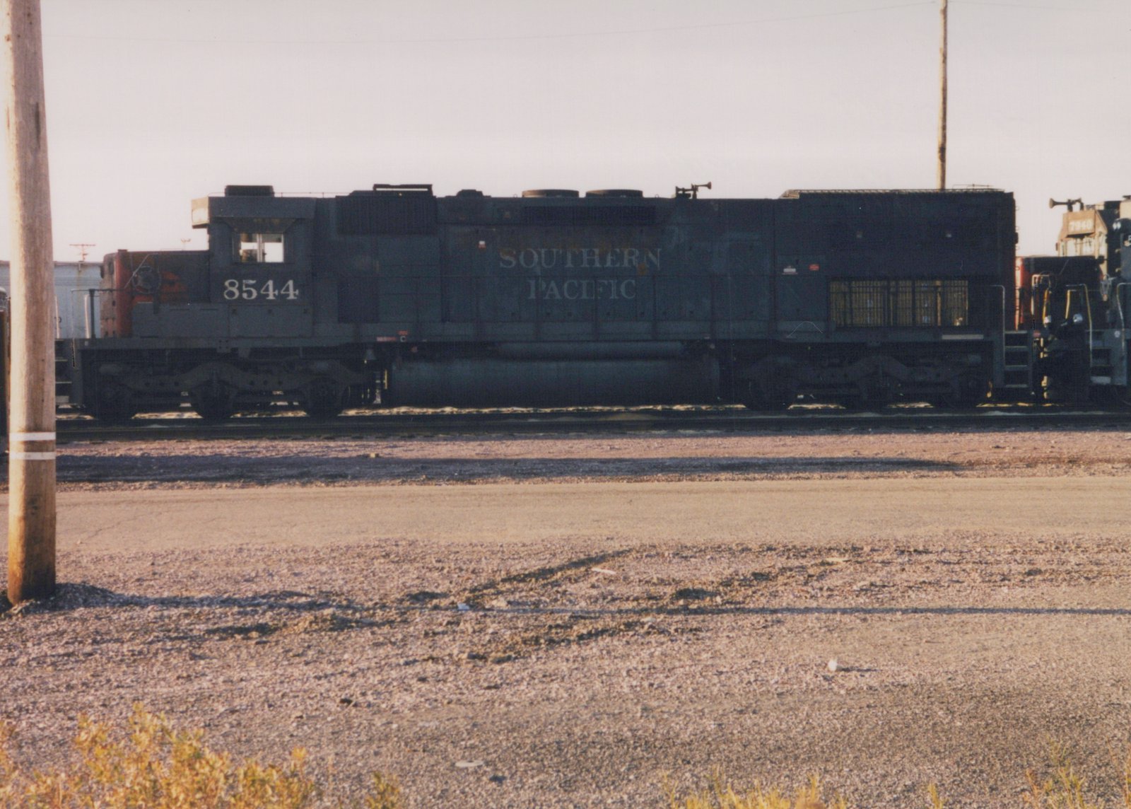 Side view of a Southern Pacific diesel locomotive, number 8544, in a gravel yard with another locomotive partially visible behind it.