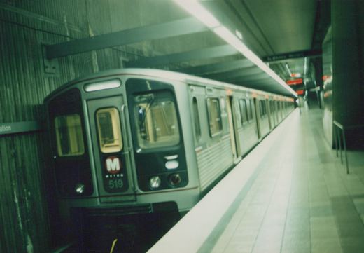 A silver CTA subway car with the number 519 and 'M METRO' logo is stopped at an underground station platform, with an overhead sign reading 'To Western - Western'.