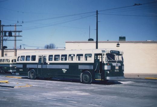Two green and white Chicago Transit Authority buses, numbers 5172 and 5213, are parked in a snowy lot with utility poles and wires overhead.