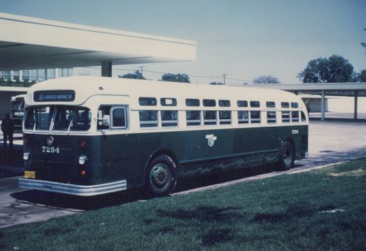 A green and white Chicago Transit Authority bus, number 7294, is parked in front of a modern terminal building with a clear blue sky in the background.