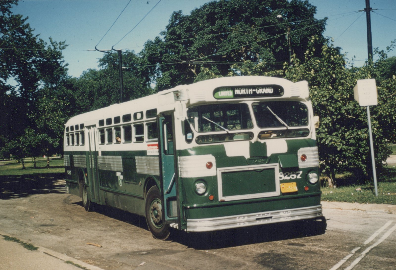 A green and white CTA motor bus numbered 8287 is parked on a tree-lined street on a clear summer day, with its destination sign reading 'NORTH LIMITED NORTH-GRAND'.