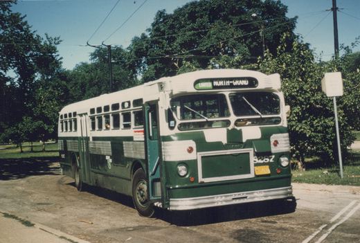 A green and cream trolleybus with the number S287 and destination sign reading 'NORTH LIMITED NORTH-GRAND' is parked on a paved street next to trees, with overhead wires above.