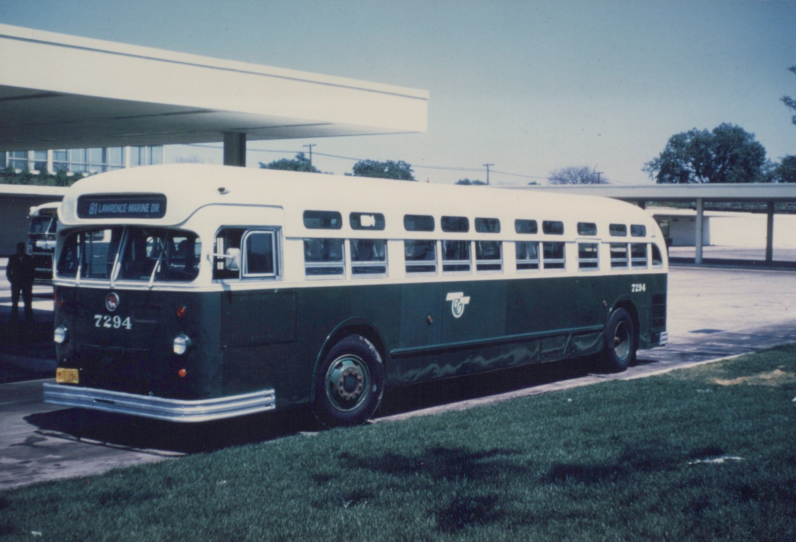 A vintage CTA bus, numbered 7294, in green and cream livery, is parked at an outdoor terminal with a clear sky in the background.